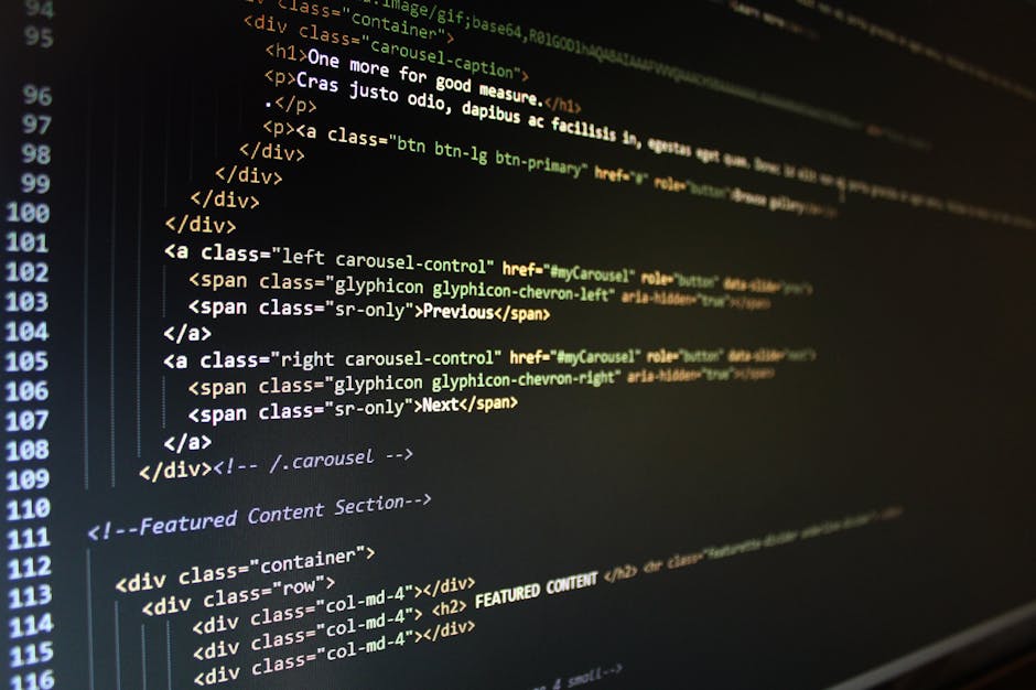 A close-up view of a person's hands typing on a laptop keyboard placed on a dark surface. The laptop screen displays a code editor with multiple lines of programming code in various colors, including 